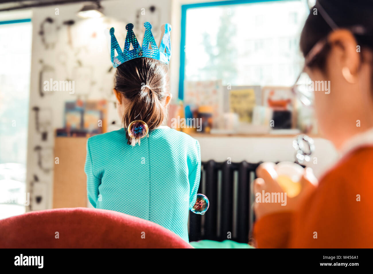 Curious girls in festive outfits being happy with soap bubbles Stock Photo