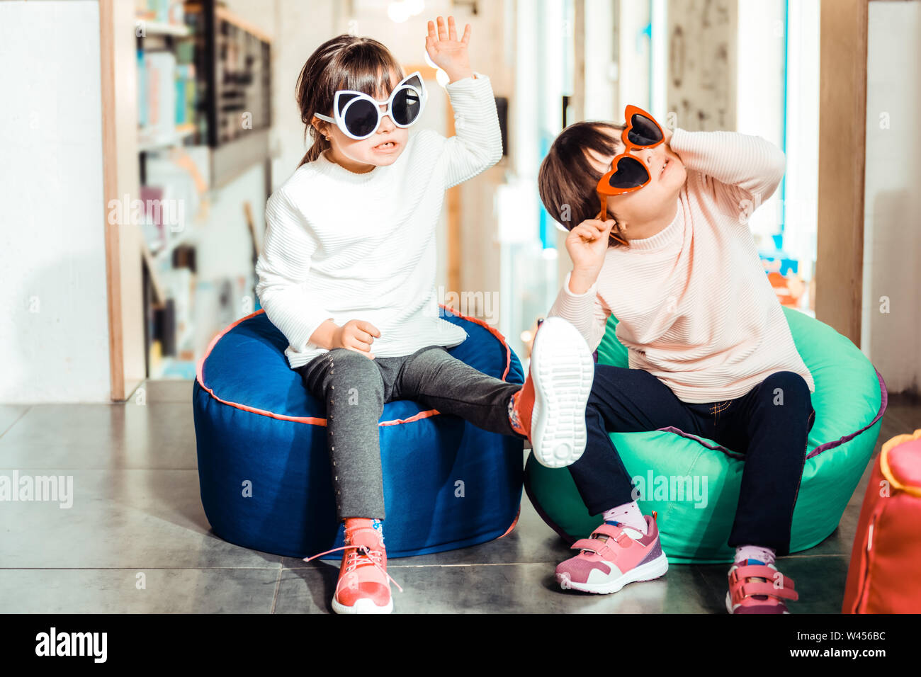 Peaceful young sisters with down syndrome wearing light sweaters Stock Photo