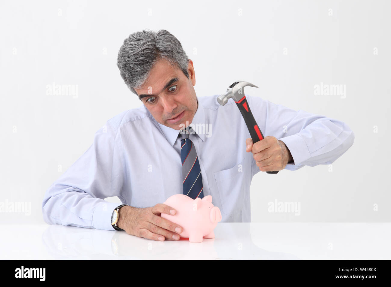 Businessman using hammer to smash a piggybank Stock Photo - Alamy