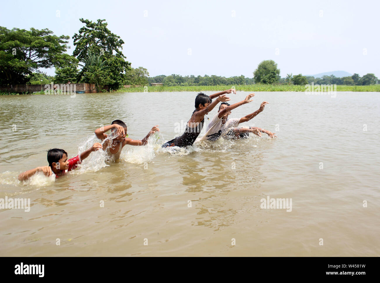 Assam. 19th July, 2019. Children play in the water as the flood caused by incessant rain hits Hajo in India's northeastern state Assam, on July 19, 2019. The combined death toll in devastating floods in India's northeastern state of Assam and eastern state of Bihar has gone up to 119, official sources told Xinhua on Friday. Credit: Stringer/Xinhua/Alamy Live News Stock Photo