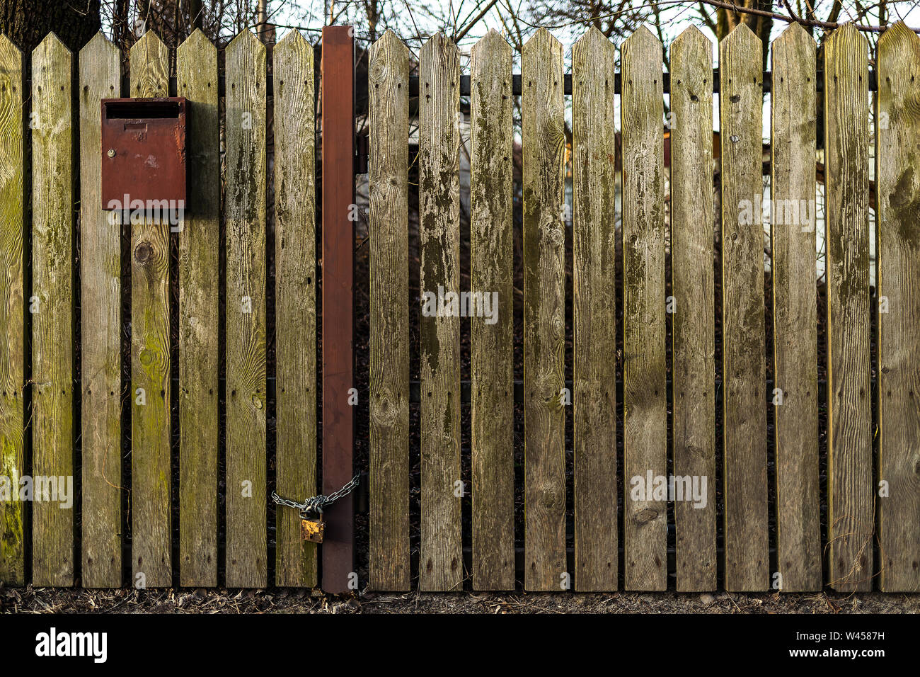 Wooden fence with a letterbox. Chain with a padlock. Waiting for a message. Stock Photo
