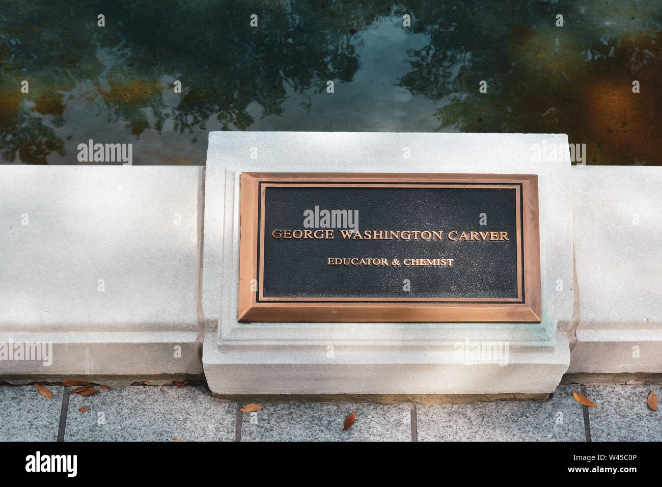 A bronze plaque commenorating George Washington Carver, Educator & Chemist, on the reflecting pool border on the RSA Tower Complex in Montgomery, AL, Stock Photo