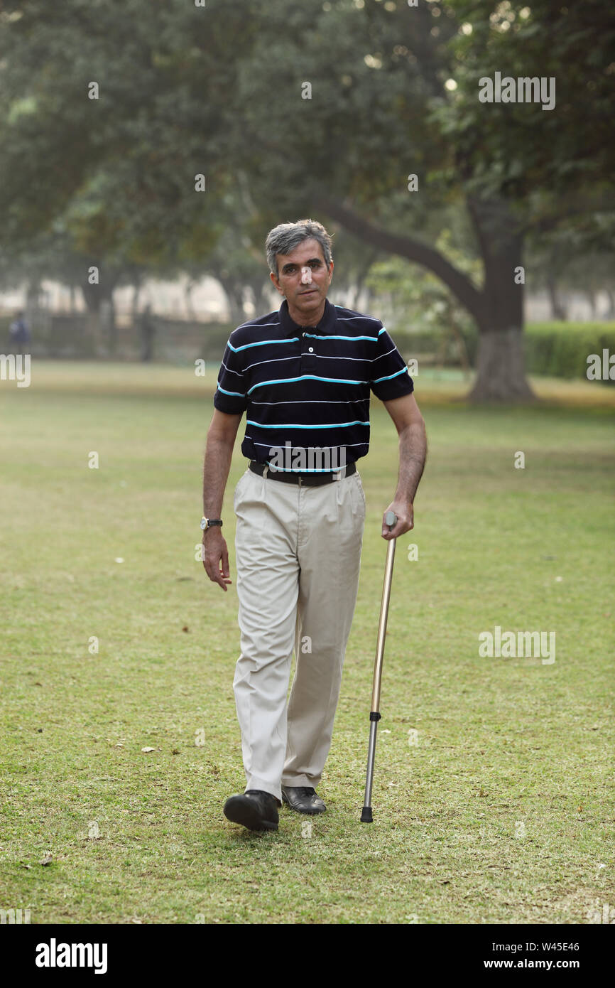 Man walking in a park with a cane Stock Photo - Alamy
