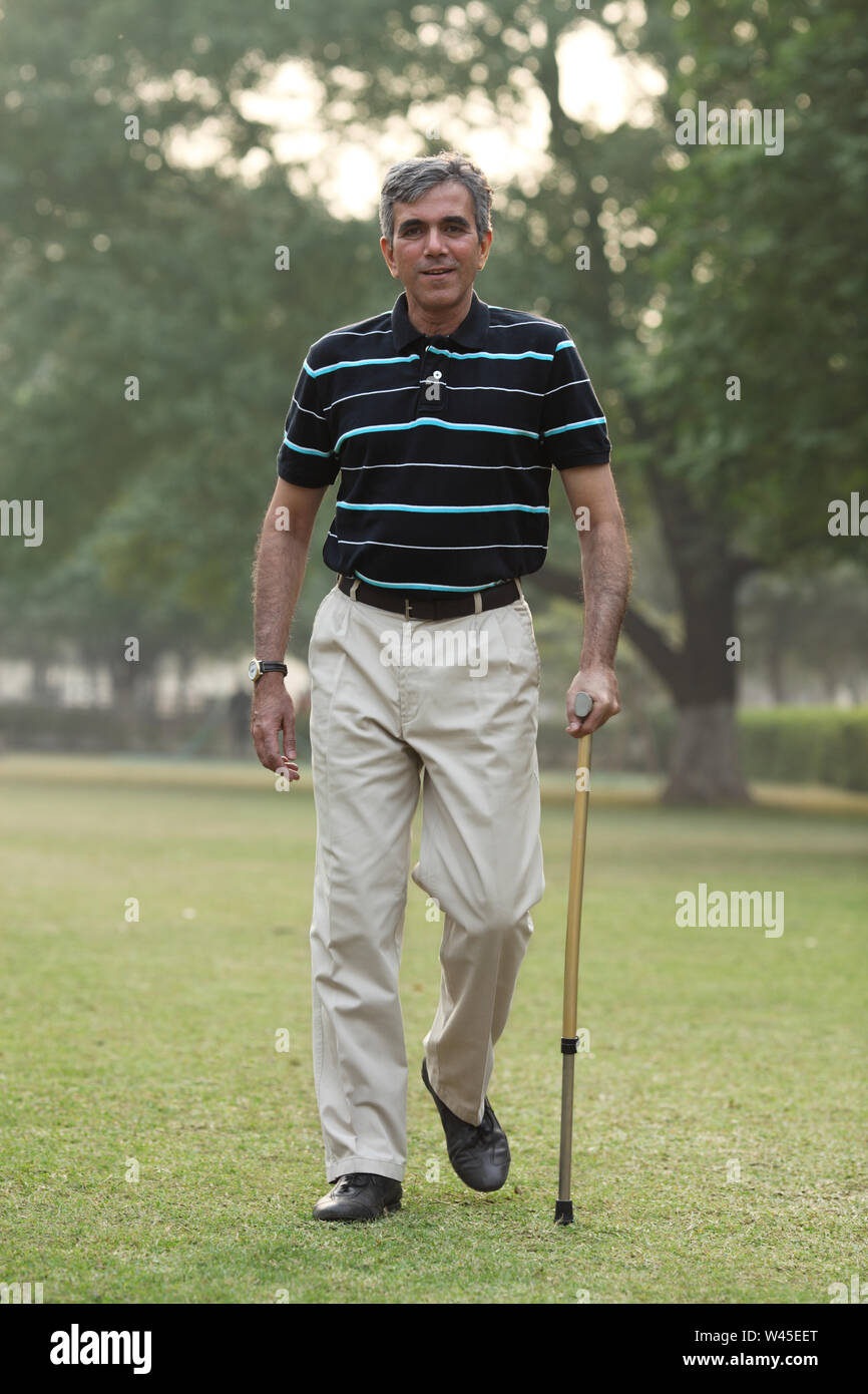 Man walking in a park with a cane Stock Photo - Alamy