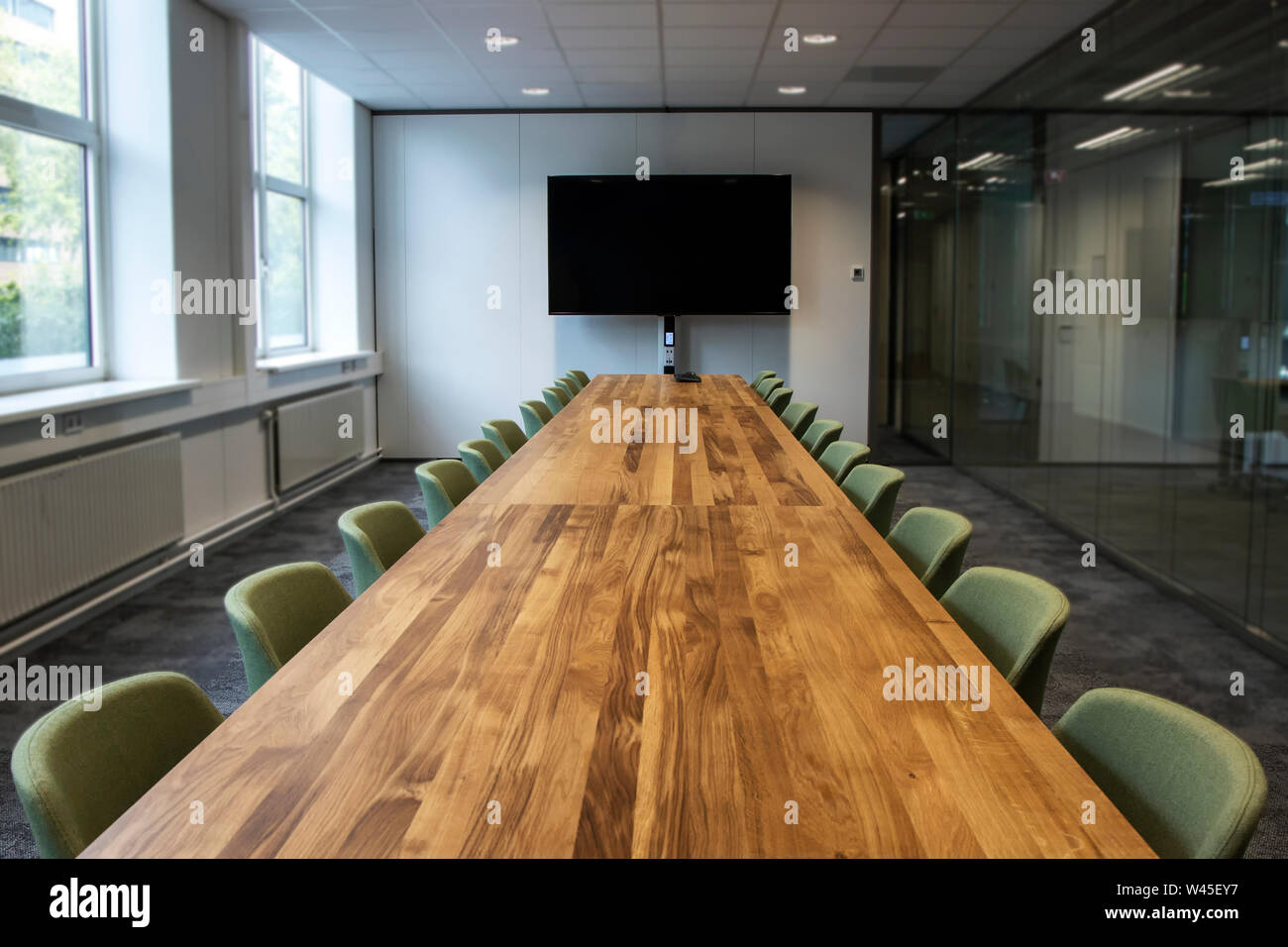 Meeting room or Board room with empty presentation LCD screen at the head of the table in modern office. Office closed work from home coronavirus. Stock Photo