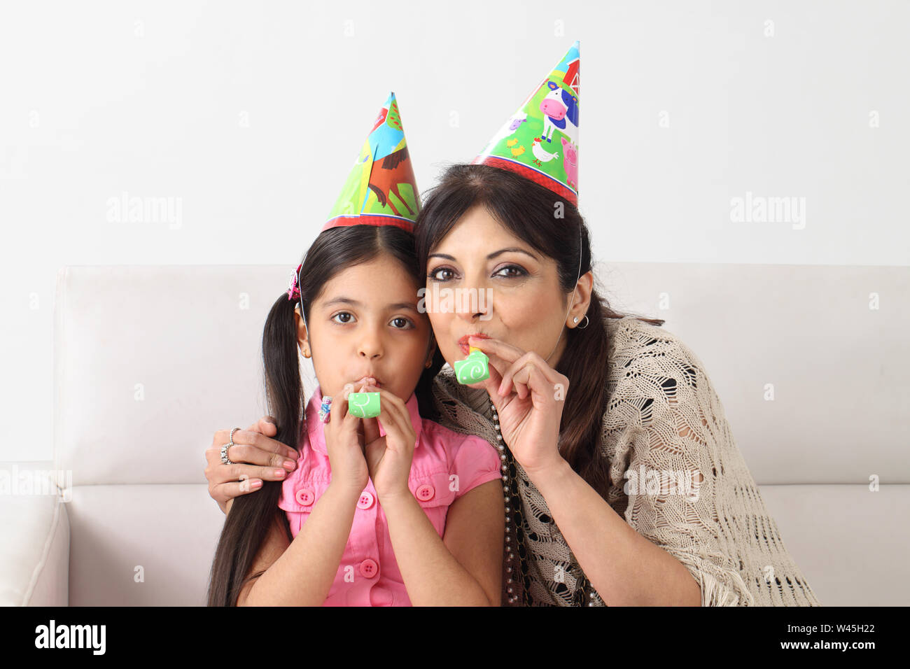 Mother and daughter blowing party blower Stock Photo - Alamy