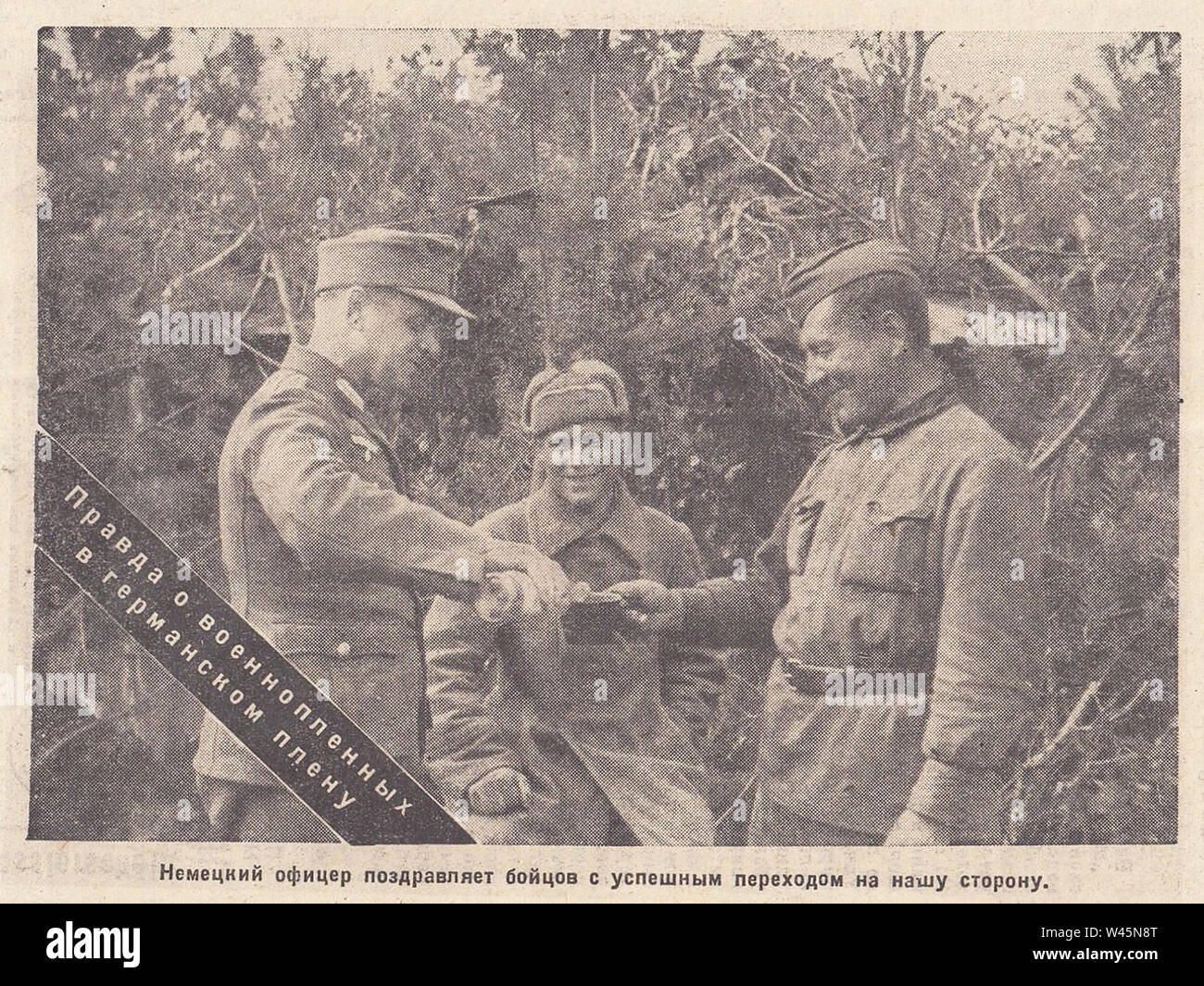 German officer congratulates Soviet fighters with a successful transition to their side. The truth about prisoners of war in German captivity. Photo from the newspaper of the 1940s. Stock Photo