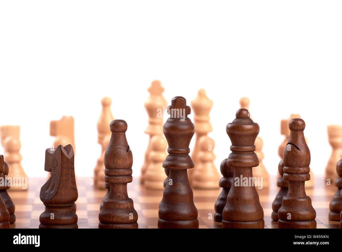 Row of white and black wooden chess pieces on a chessboard, with selective focus, isolated on white background. Stock Photo