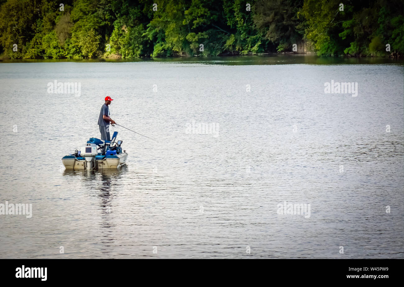 An Africian America man fishing from his powerboat in the middle of the river in the Southeastern USA Stock Photo