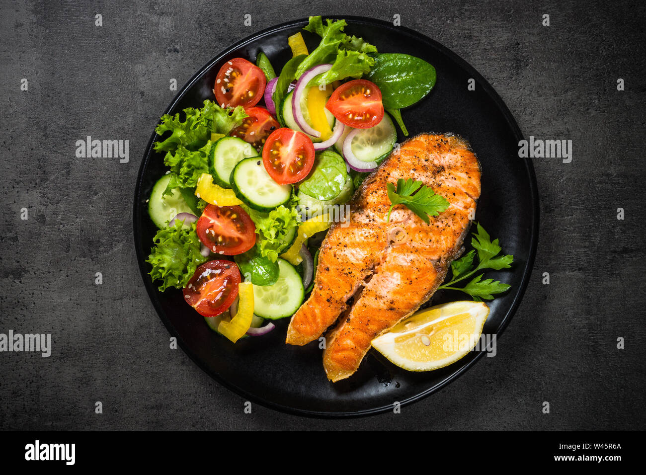 Grilled salmon fish steak with vegetables on black Stock Photo - Alamy