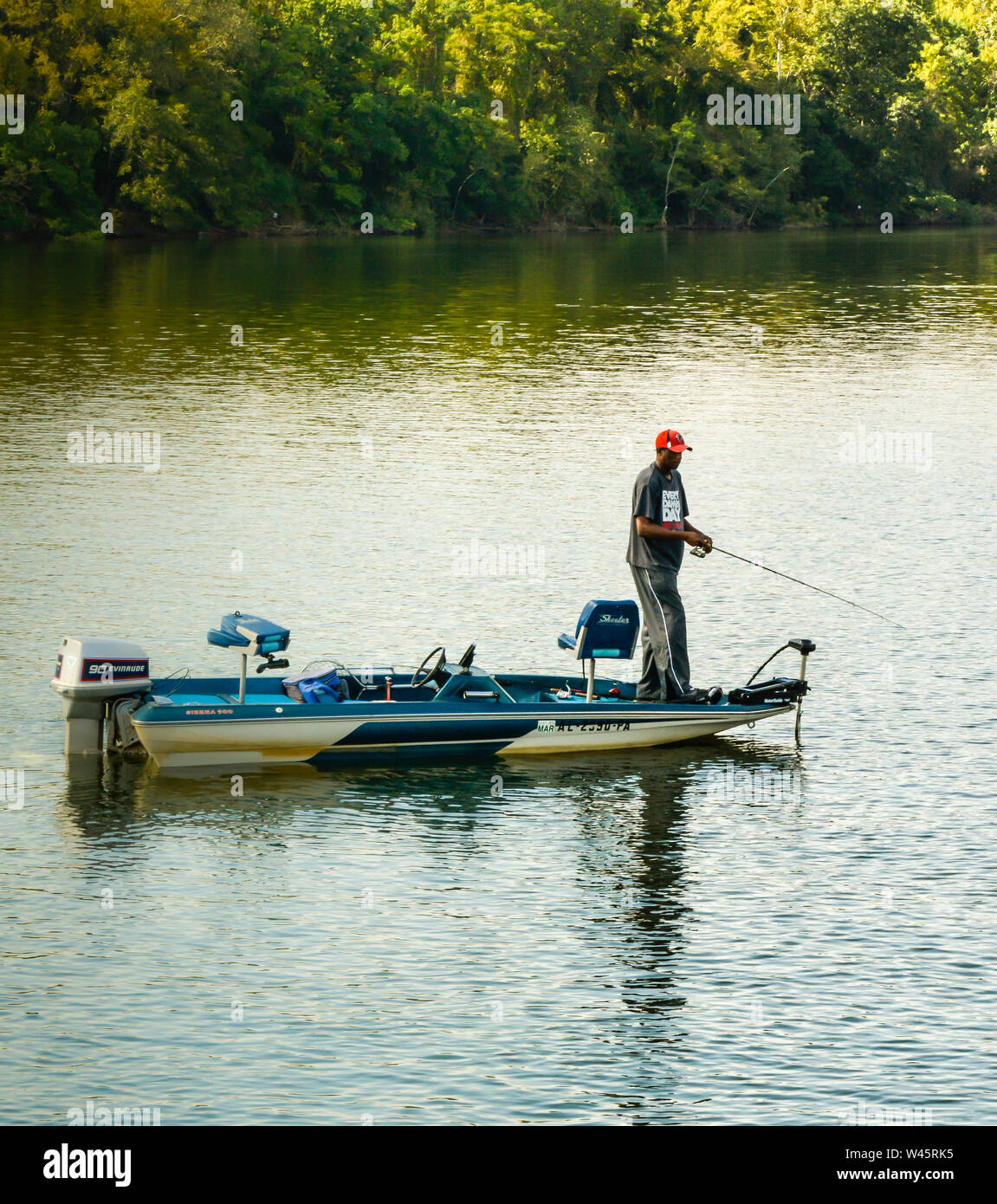 An African America man fishing from his motor boat at sundown, in the middle of the river in the Southeastern USA, Stock Photo