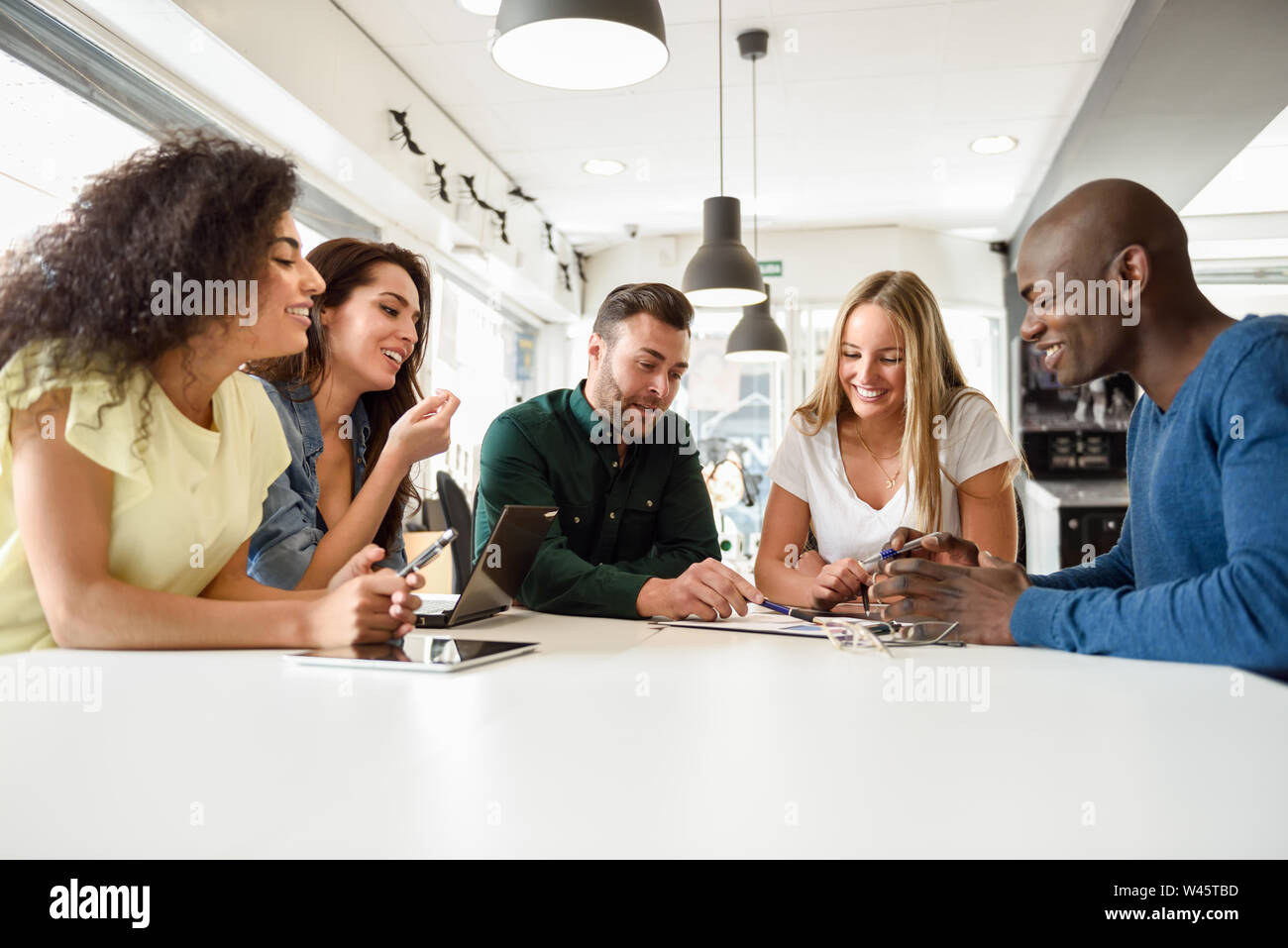 Multi-ethnic group of young people studying together on white desk Stock Photo