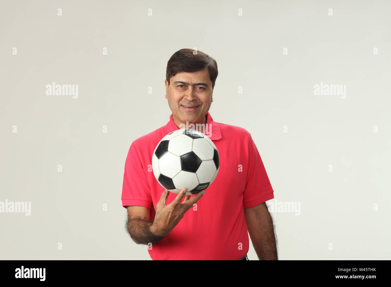 Portrait of a man holding a soccer ball and smiling Stock Photo - Alamy