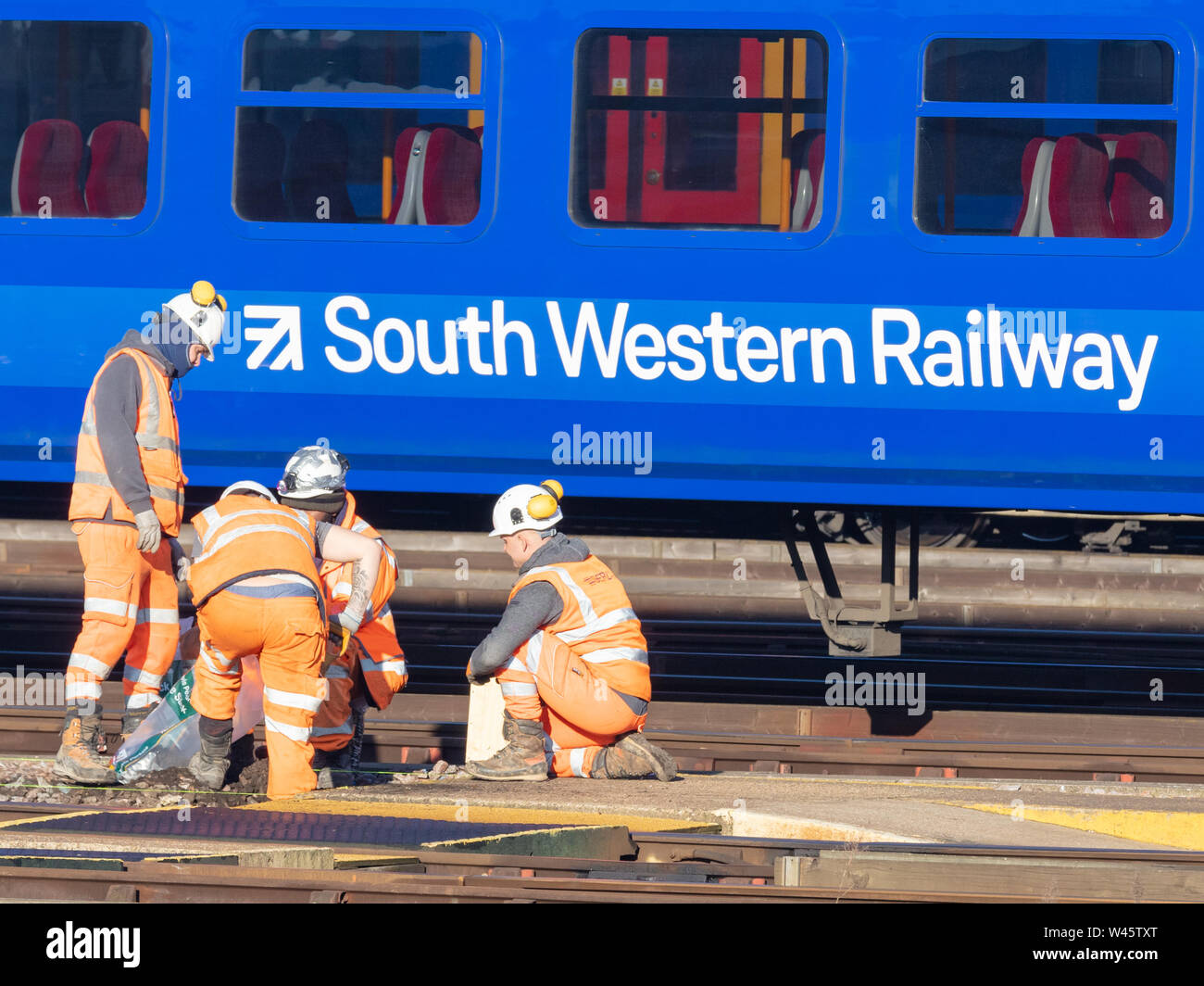 Clapham Junction, London, UK; 14th February 2019; Group of Rail Workers Working Trackside With South Western Railway Train Behind Stock Photo