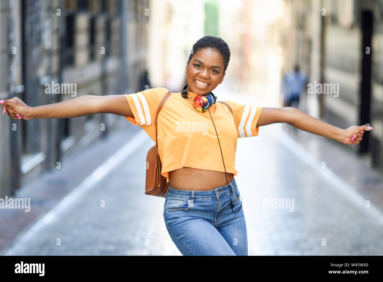 Young black woman is dancing on the street in Summer. Girl traveling alone. Stock Photo