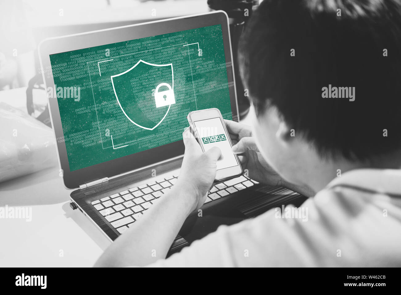 Network internet devices security and online data security system technology. a man using mobile phone verification password on computer laptop Stock Photo