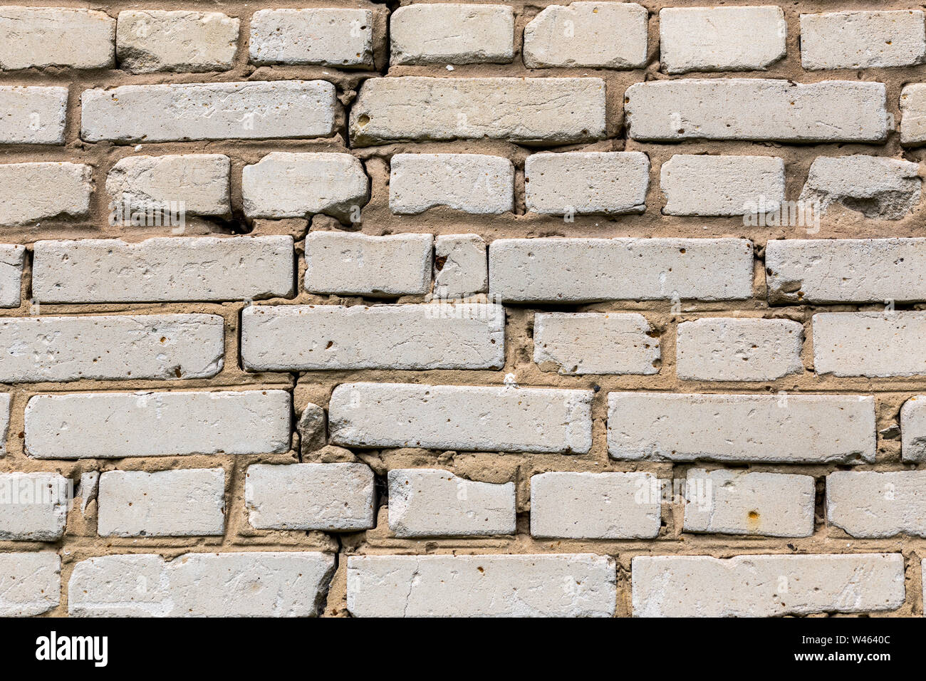 Deep cracked white silicate brick wall closeup texture and background. Horizontal shot. Stock Photo
