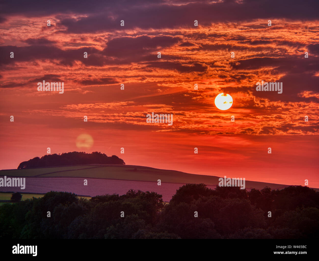 Weather UK: strange hazy red sunset over Aleck Low optical Lens distortion giving the appearance of two suns or the full buck moon refracting 180 degrees around the earth. It’s not lens flare as there is cloud over the second sun 16/07/2019, Aleck Low, shot from near Minninglow carpark, Pikehall, Peak District National Park, Derbyshire, UK Stock Photo
