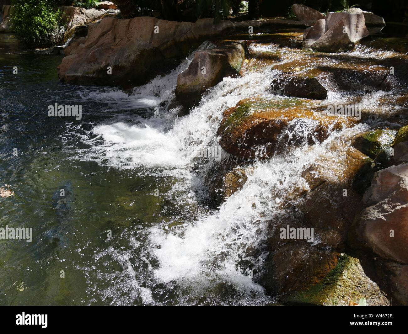 Close up, side view of water cascading down rocks in a landscaped ...