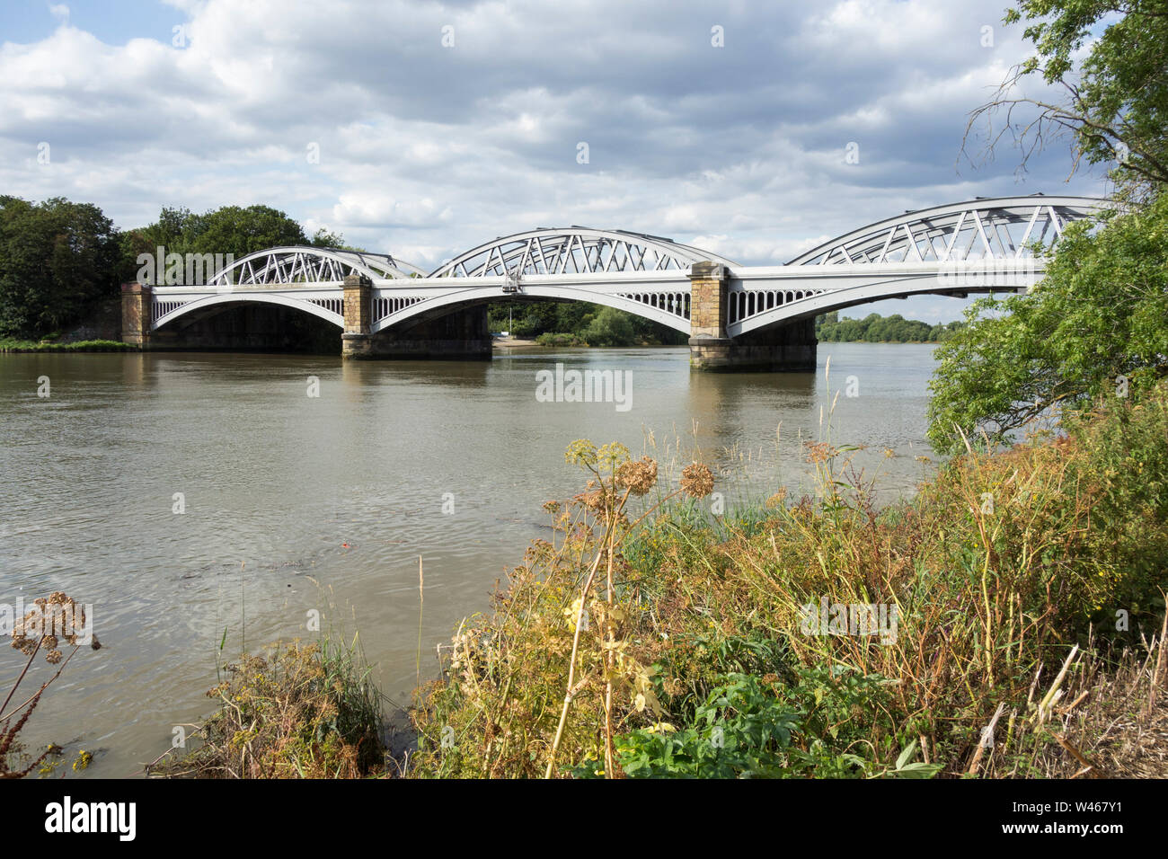 The River Thames flowing peacefully under Joseph Locke's Barnes Railway Bridge, Barnes, London, UK Stock Photo