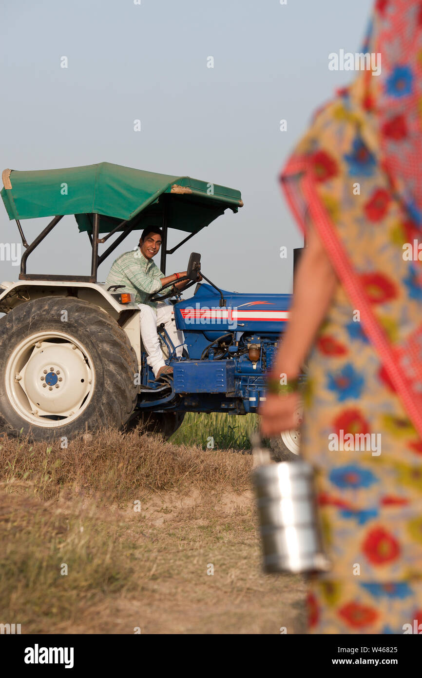 Farmer sitting on tractor and his wife walking with lunch Stock Photo ...