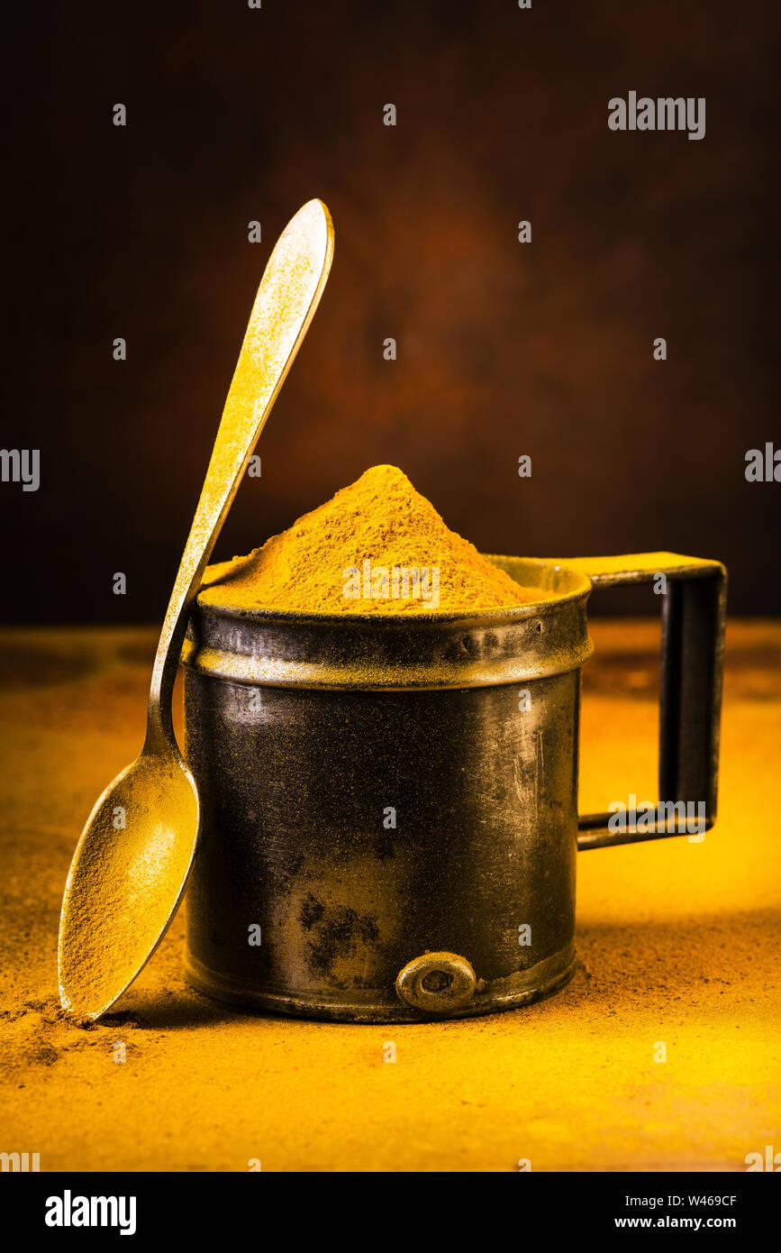 still life, closeup of turmeric powder on the table and in the vintage metal measuring spoon Stock Photo