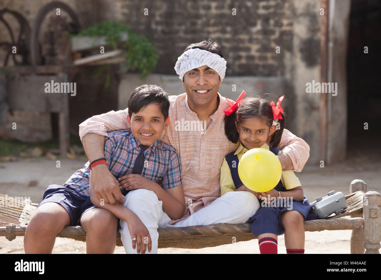 Family sitting on string cot and smiling Stock Photo