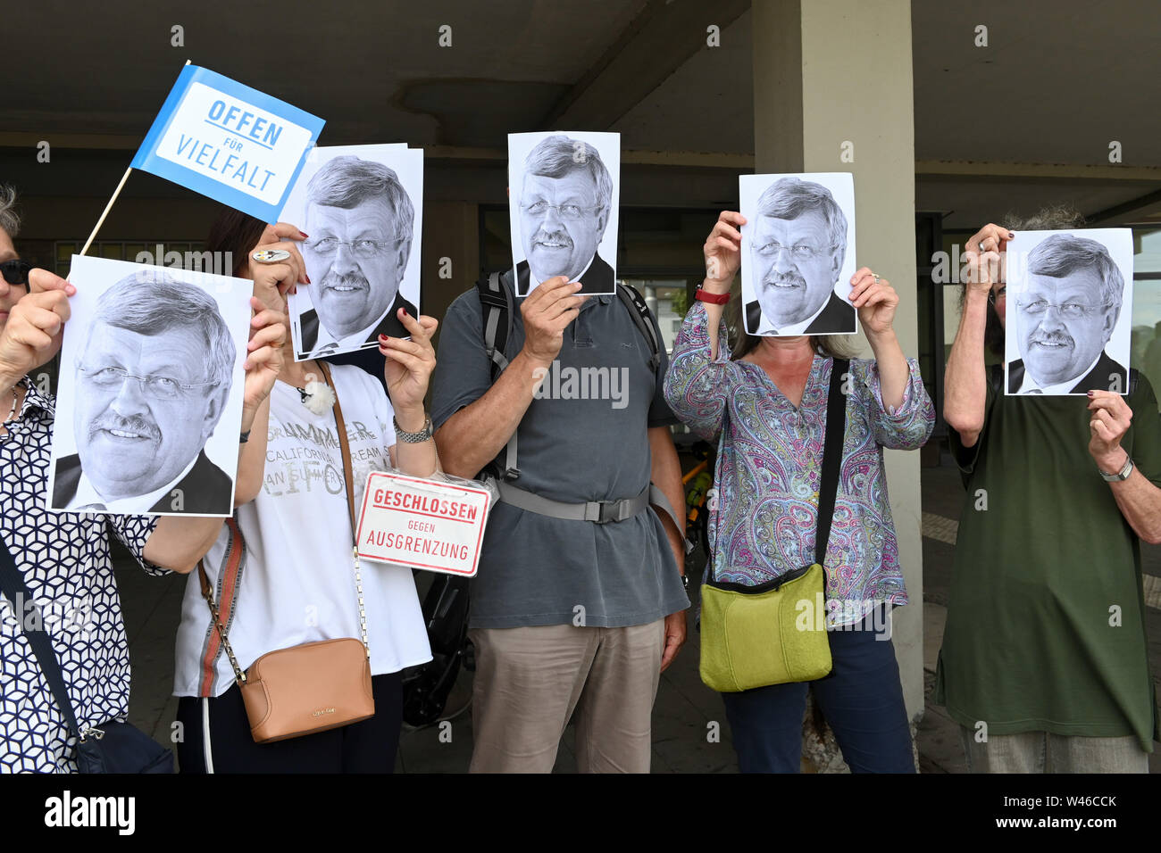 Kassel, Germany. 20th July, 2019. Demonstrators against the march of the smallest party 'Die Rechte' hold portraits of the shot Walter Lübck in front of their faces. The party had called for a demonstration in Kassel against media prejudgement in connection with the Lübcke case. A massive police presence is to prevent possible riots between the two camps. Credit: Uwe Zucchi/dpa/Alamy Live News Stock Photo