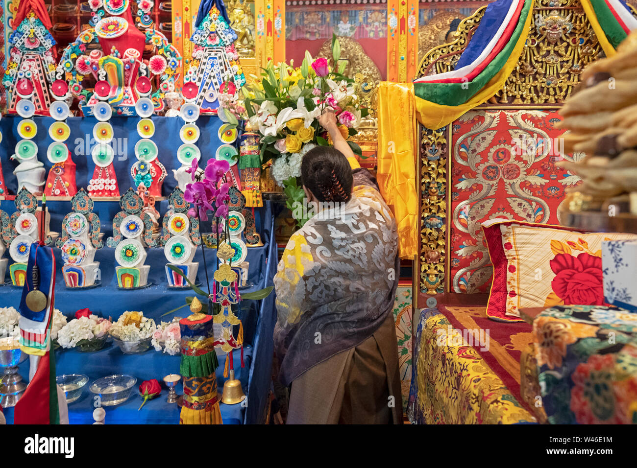 A devout Nepalese Sherpa Buddhist worshipper decorates the temple altar