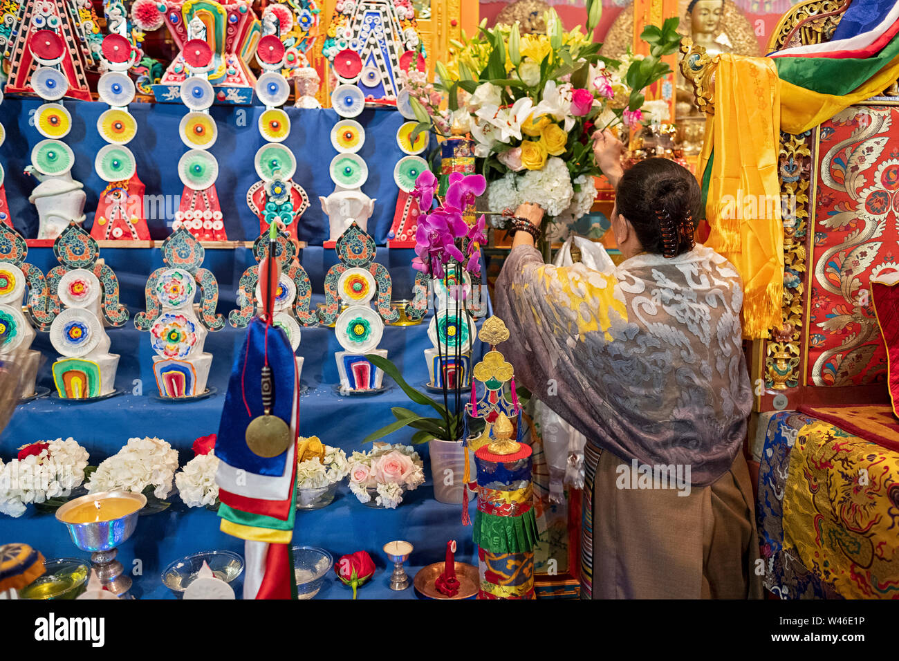 A devout Nepalese Sherpa Buddhist worshipper decorates the temple altar