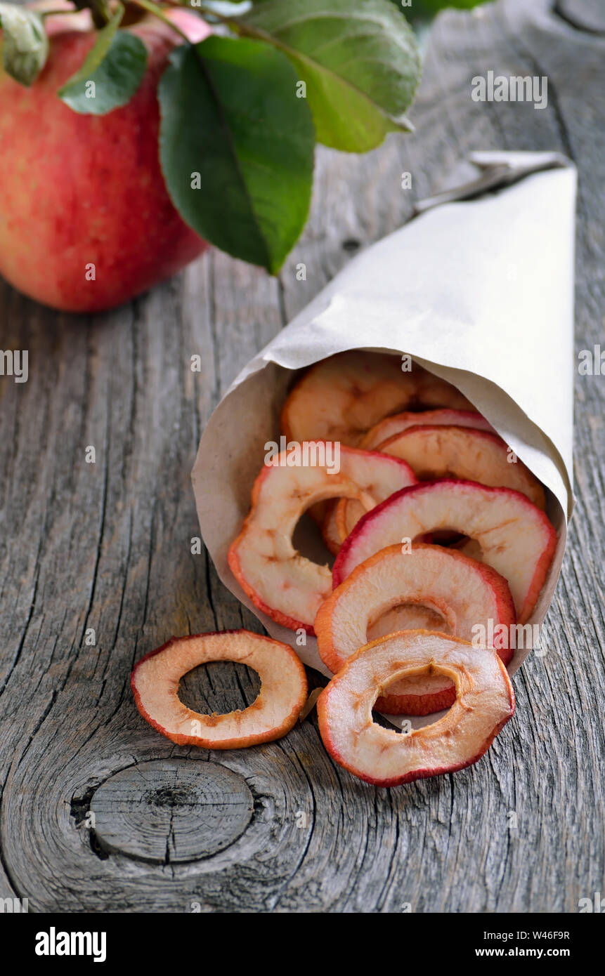 Dehydrated apples chips in paper bag on rustic table Stock Photo