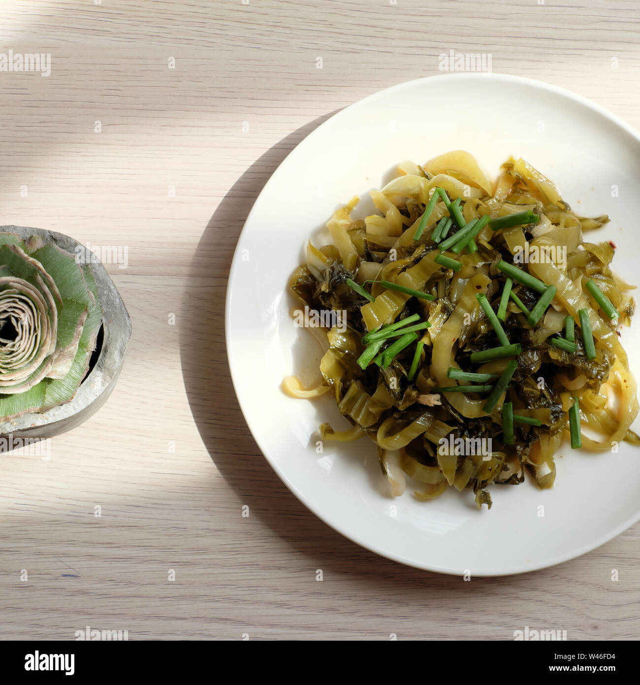 Plate of homemade food, sour mustard or sour vegetable fry with cooking oil and scallion on white background from top view Stock Photo