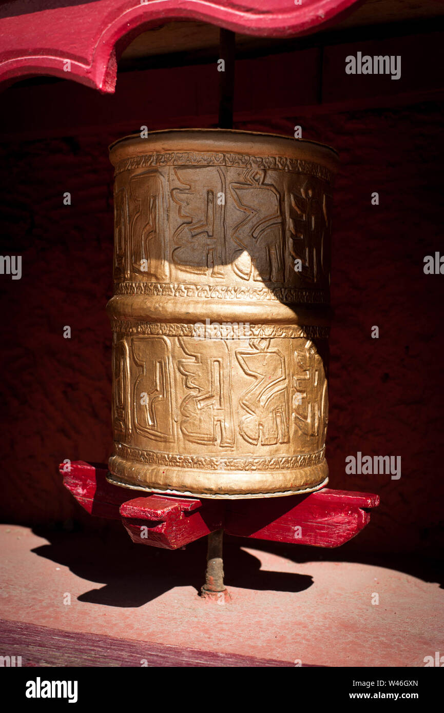 Buddhist Prayer wheel decorated with Sanskrit symbols at Tibetan monastery. Ornate rotating traditional cylinder with text of mantra written on it for Stock Photo