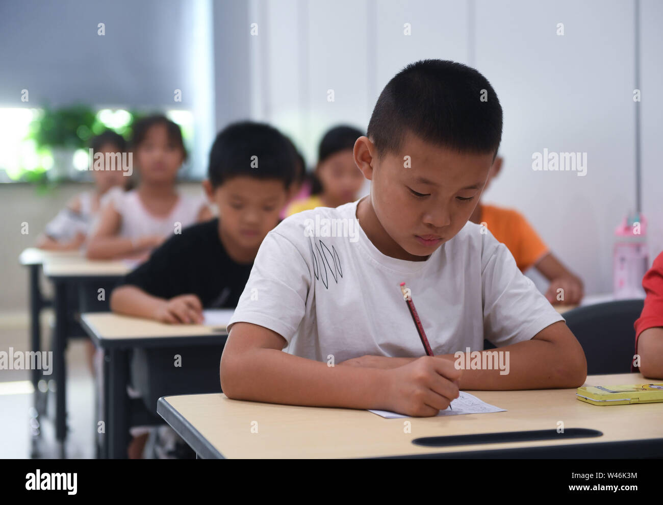 (190720) -- HAINING, July 20, 2019 (Xinhua) -- Children practice handwriting as part of a summer camp organized by a local company for the children of its migrant workers in Haining, east China's Zhejiang Province, July 20, 2019. Running for 40 days starting from mid-July, the summer camp invites 180 children whose parents work for the company away from home and thus offers them a chance for family reunion. Besides, the children can expect an enriched summer life here by taking academic, etiquette and sports courses given by university volunteer tutors. (Xinhua/Xu Yu) Stock Photo