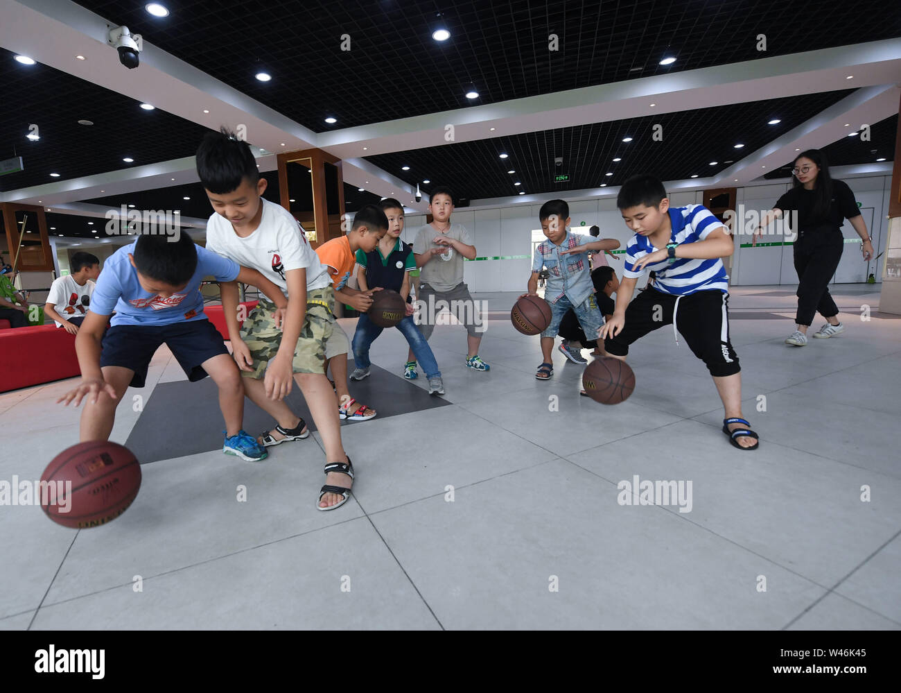 (190720) -- HAINING, July 20, 2019 (Xinhua) -- A basketball class is given as part of a summer camp organized by a local company for the children of its migrant workers in Haining, east China's Zhejiang Province, July 20, 2019. Running for 40 days starting from mid-July, the summer camp invites 180 children whose parents work for the company away from home and thus offers them a chance for family reunion. Besides, the children can expect an enriched summer life here by taking academic, etiquette and sports courses given by university volunteer tutors. (Xinhua/Xu Yu) Stock Photo