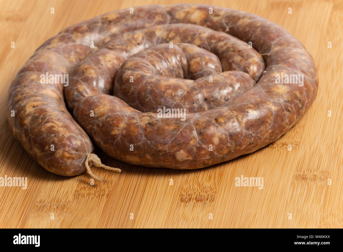Raw homemade stuffed pork sausages isolated on a woodboard. Stock Photo