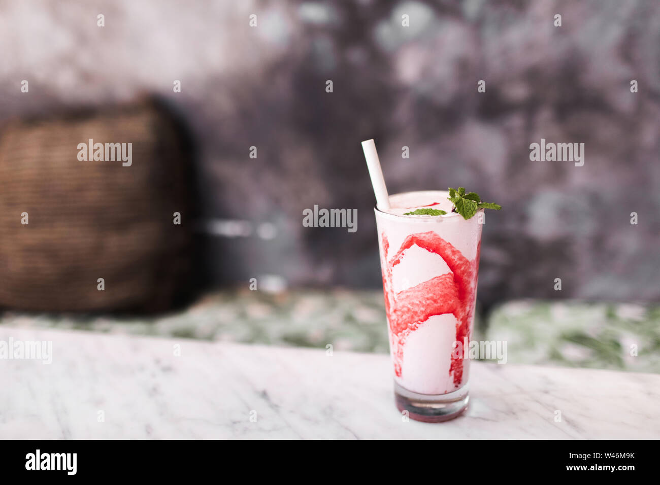 Fresh tasty cold milk shake with red strawberry syrup on white marble table. Gray concrete background. Sweet frappuccino beverage. Summer drink Stock Photo