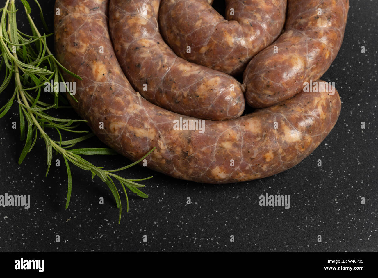 Raw homemade stuffed pork sausages and rosmarin isolated on a black background. Stock Photo
