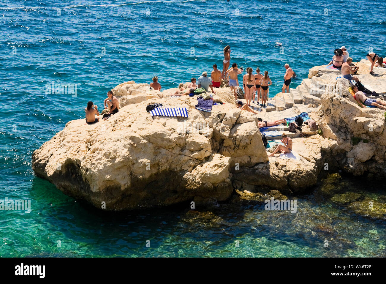 people swimming; rock beaches; relaxation; vacation; fun; clear water; Rovinj; Croatia; Europe; summer Stock Photo