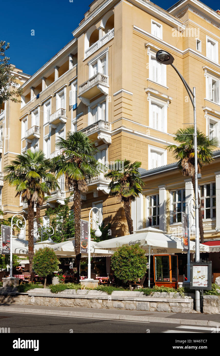 older attractive hotel, restaurant, outdoor eating, umbrellas, vacation spot, ornate lamp posts, city, Opatija; Croatia; Europe; summer, vertical Stock Photo