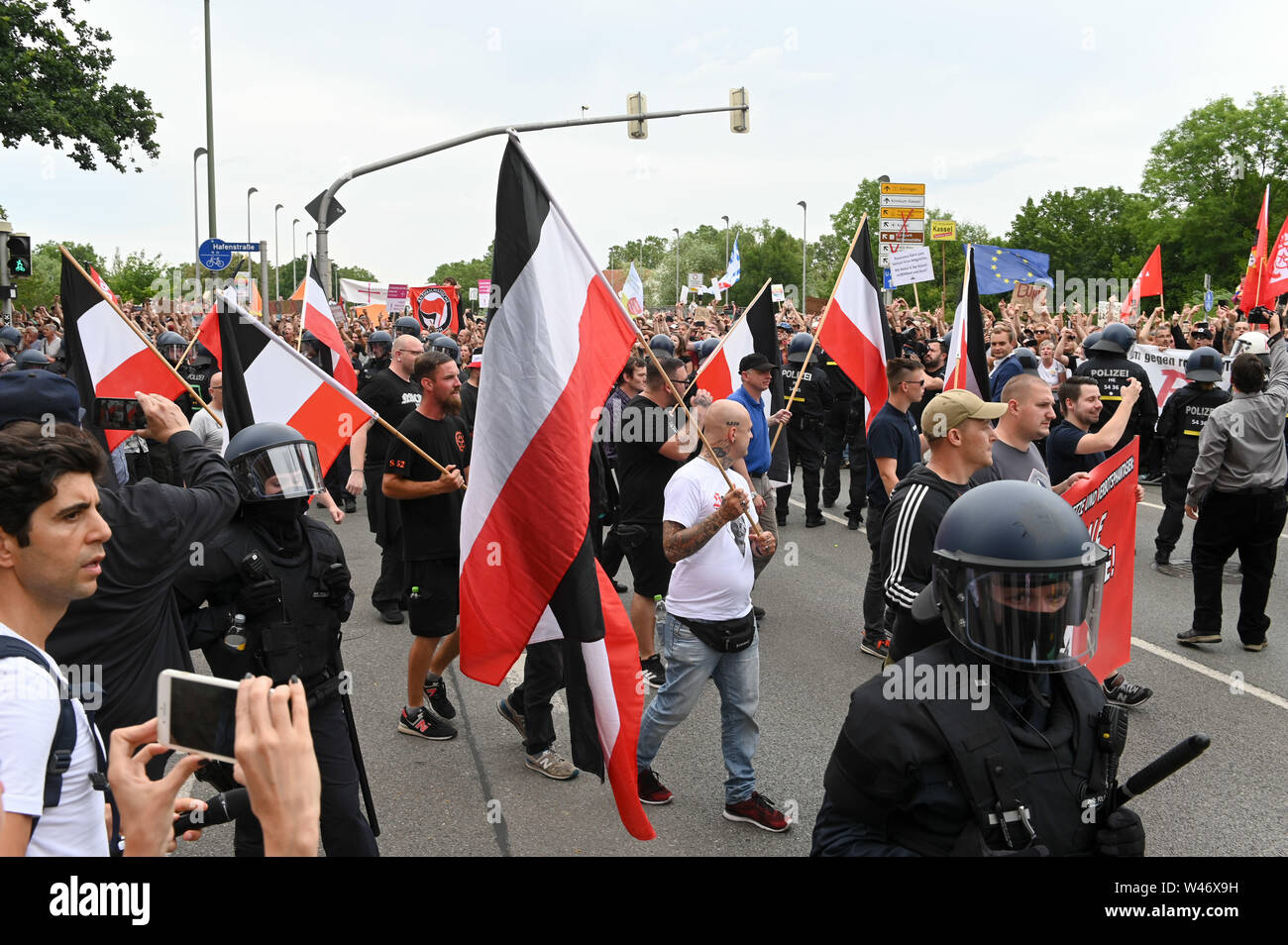 Hanover, Germany. Kassel, Germany. 20th July, 2019. Supporters of the right-wing extremist mini-party 'Die Rechte' pass by counter-demonstrators during their demonstration. The party had called for a demonstration in Kassel against media prejudgement in connection with the Lübcke case. A massive police presence is to prevent possible riots between the two camps. Credit: Uwe Zucchi/dpa/Alamy Live News Stock Photo