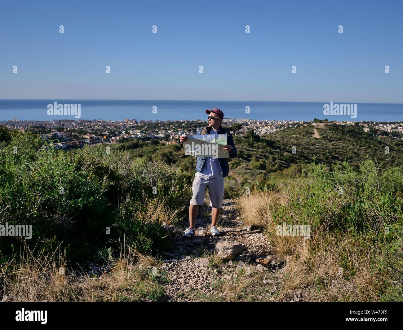 Male tourist with a map of the area stands on a stone path Stock Photo