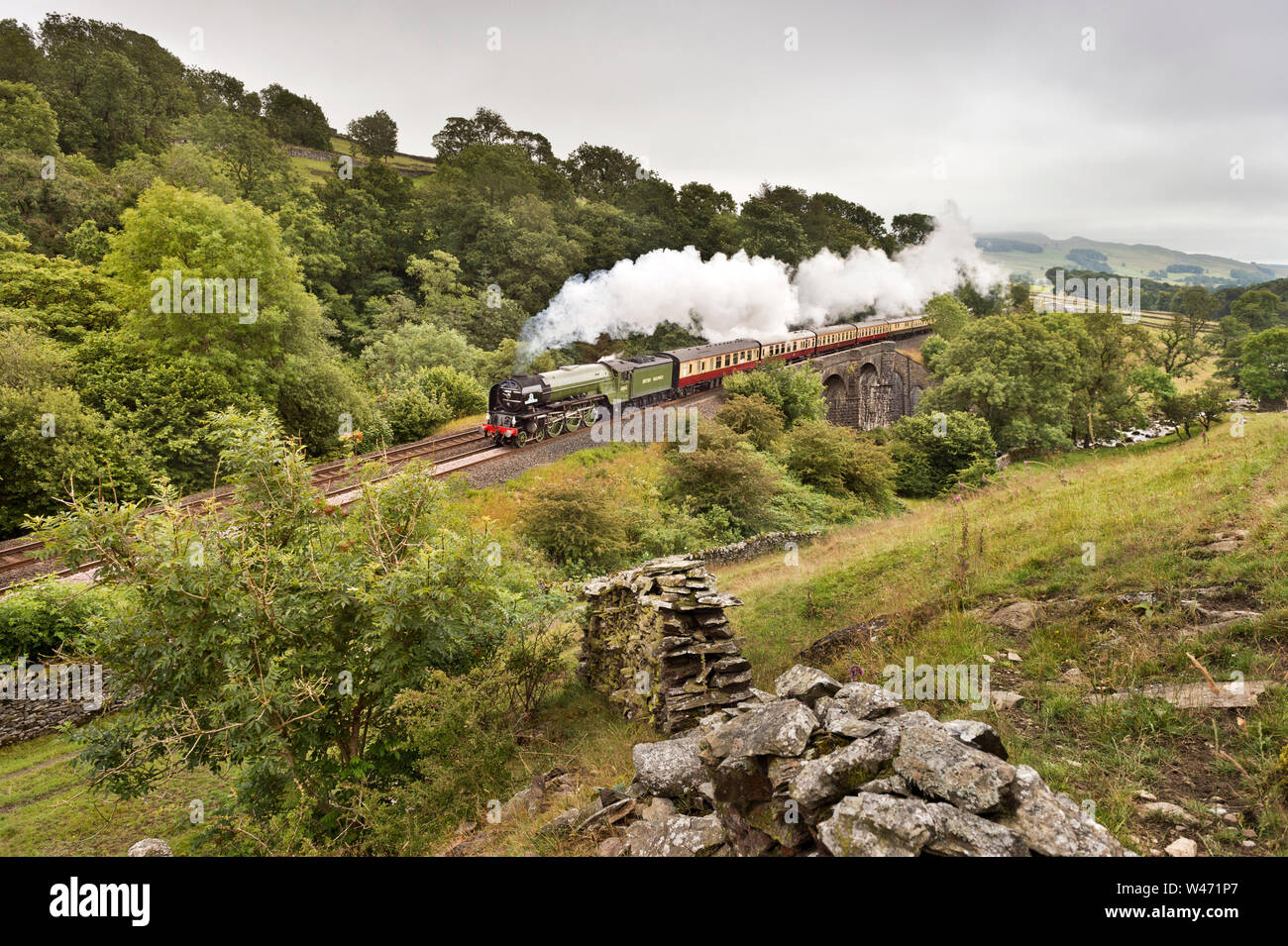 Stainforth, North Yorkshire, UK. 20th July 2019. Steam locomotive 60163  'Tornado' hauls the 'North Briton' steam special up the gradient of the Settle-Carlisle railway line towards Carlisle. Seen here at Stainforth in the Yorkshire Dales National Park, crossing Sheriff's Brow Viaduct. The excursion began and finished in London, with steam haulage over the Doncaster-Carlisle-Newcastle section of the route. The beginning and end parts of the trip were hauled by a mainline electric class 86 locomotive. Stock Photo