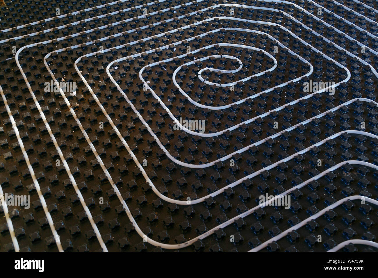 Black underfloor heating surface with heating pipes. Stock Photo
