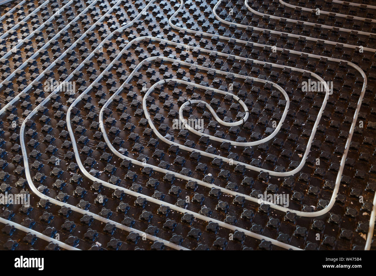 Black underfloor heating surface with heating pipes. Stock Photo