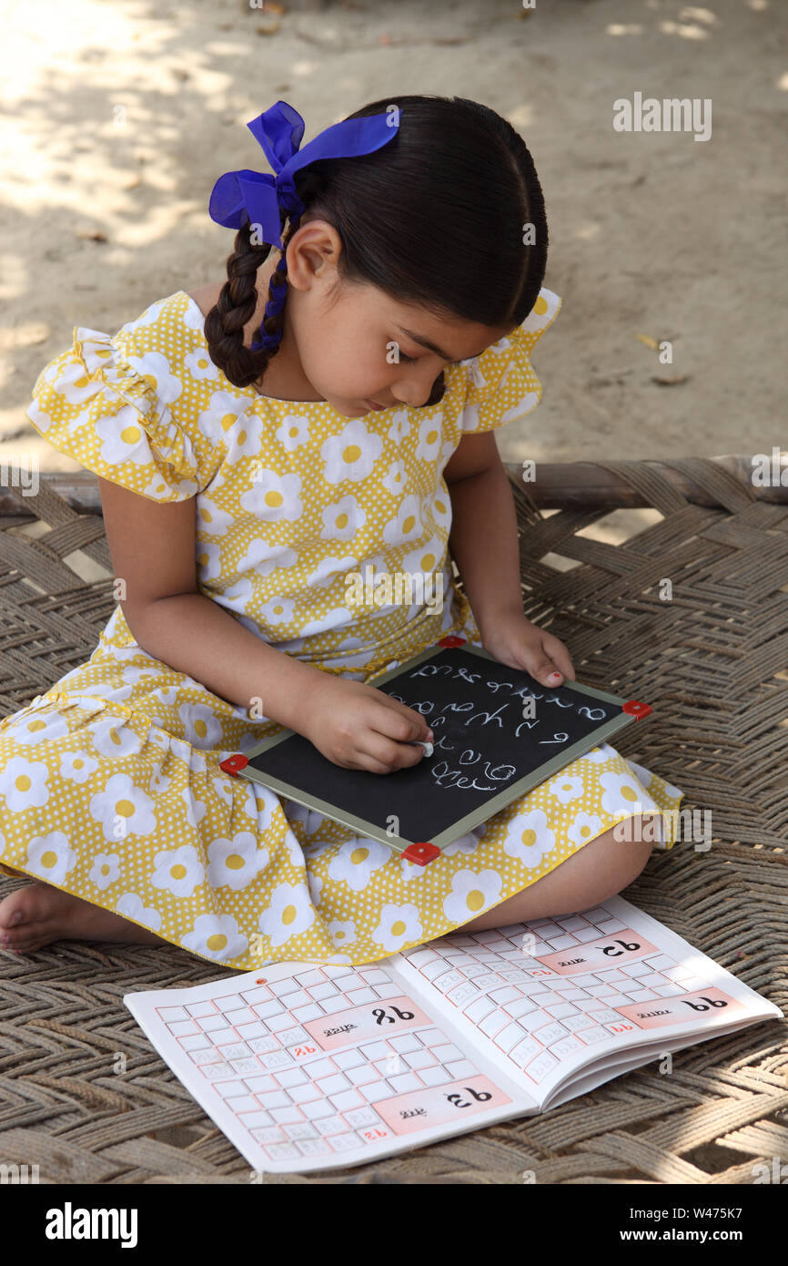 Indian girl writing numbers on a slate Stock Photo - Alamy