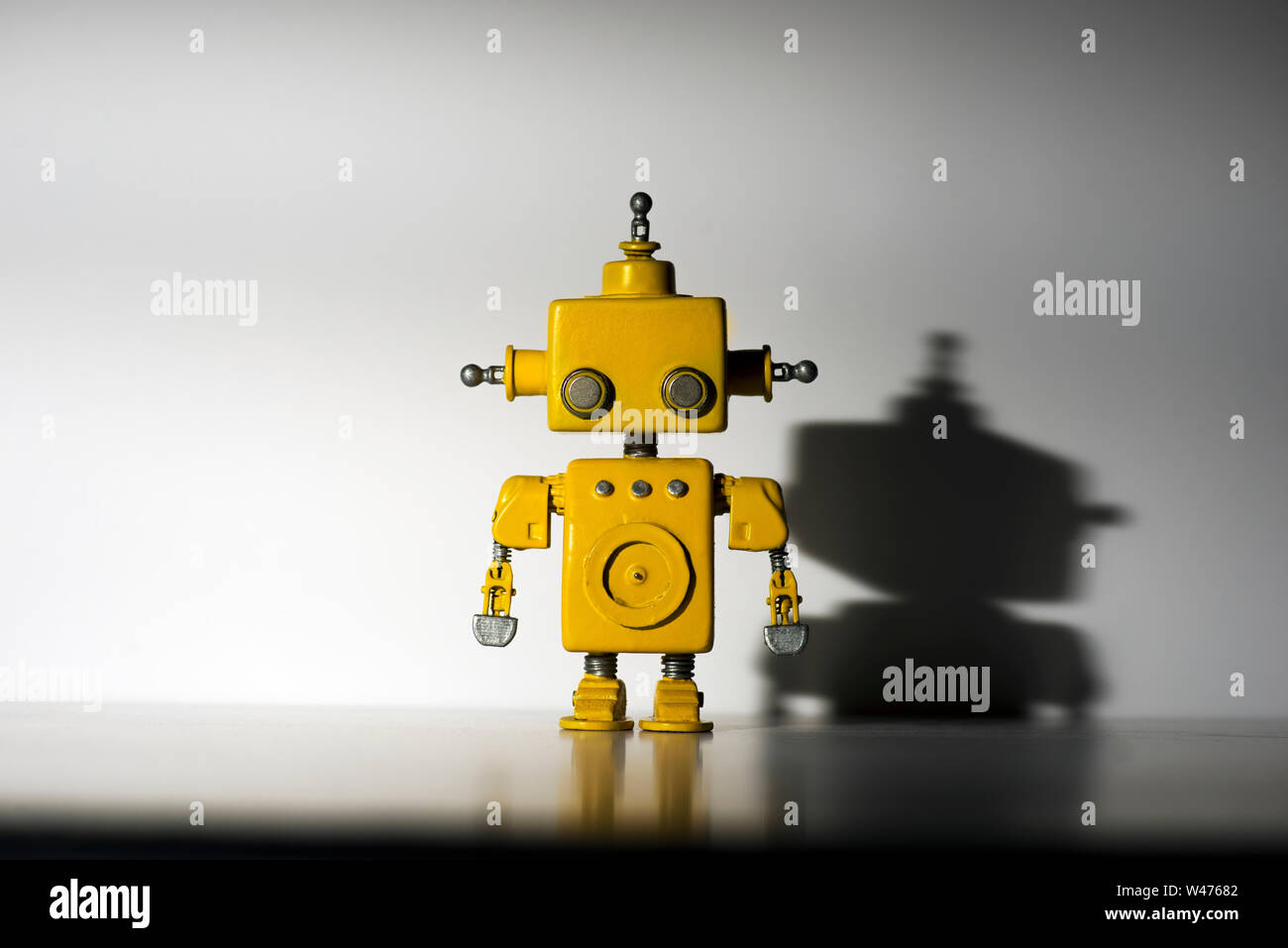 Cute, yellow, handmade robot on a white background with hard shadow ...