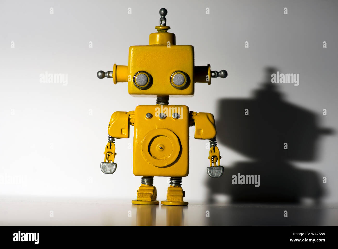 Cute, yellow, handmade robot on a white background with hard shadow ...