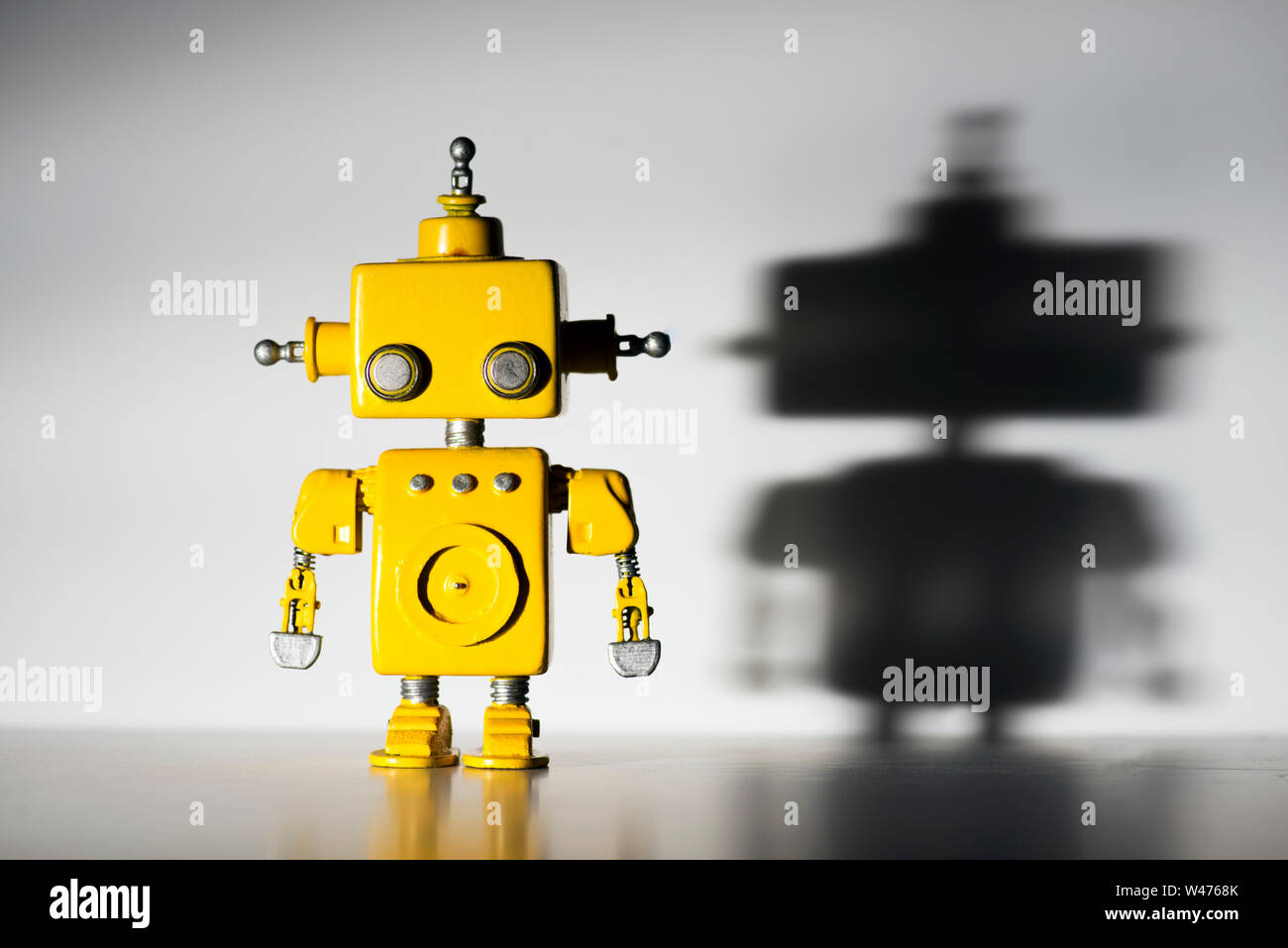 Cute, yellow, handmade robot on a white background with hard shadow ...