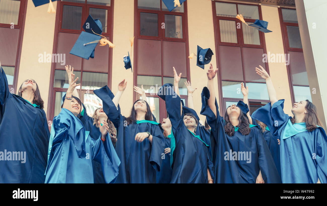 University graduates throwing graduation hats in the air. Group of ...